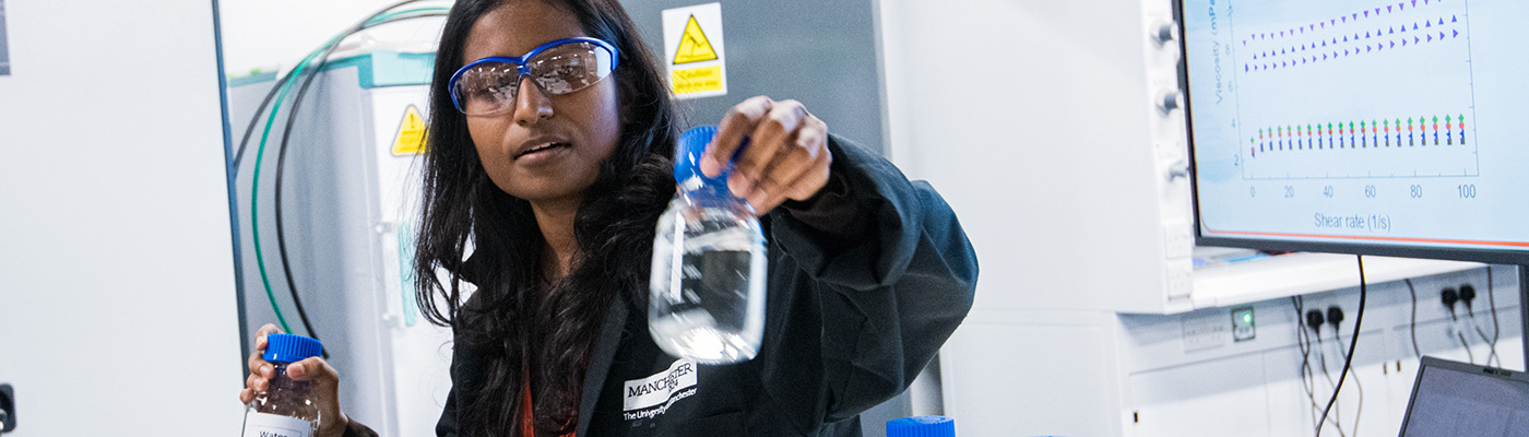 Female researcher showing a sample bottle containing graphene in solution