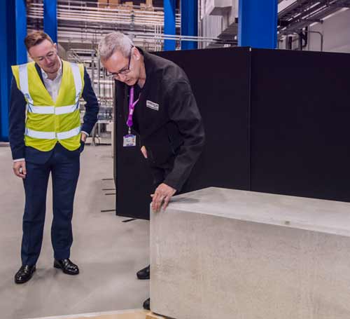 Two men stood in a factory inspecting a large concrete slab