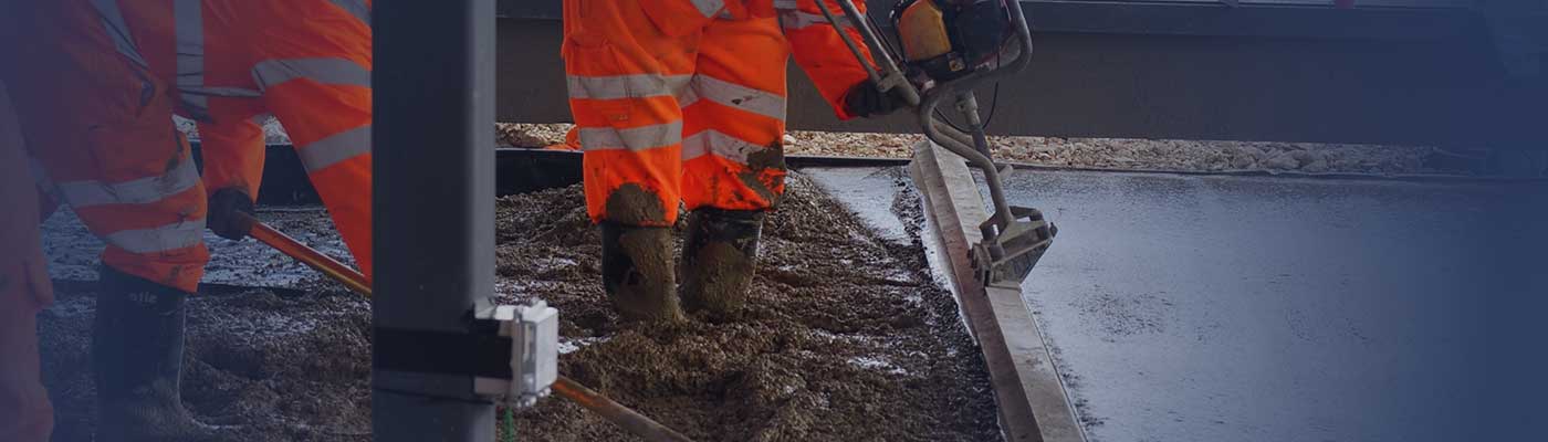 Two workmen wearing protective clothing spreading concretene.