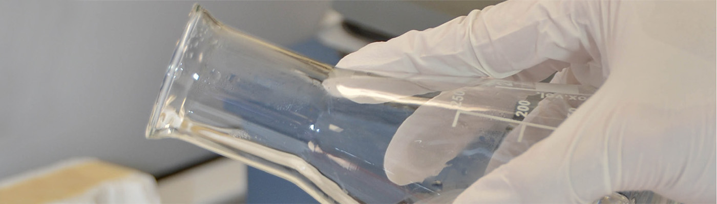 Close up of a researcher pouring from a conical flask